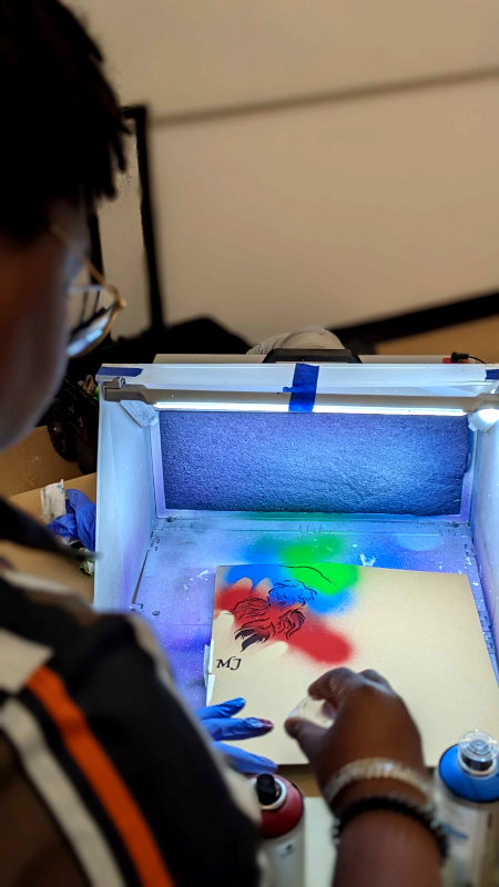 student spray painting a stencil bird