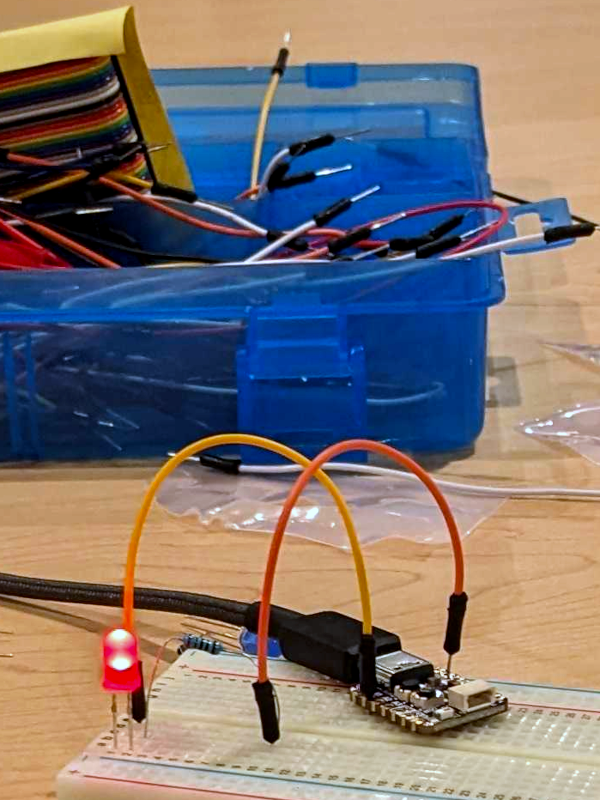 QT Py board connected to a breadboard with a red LED